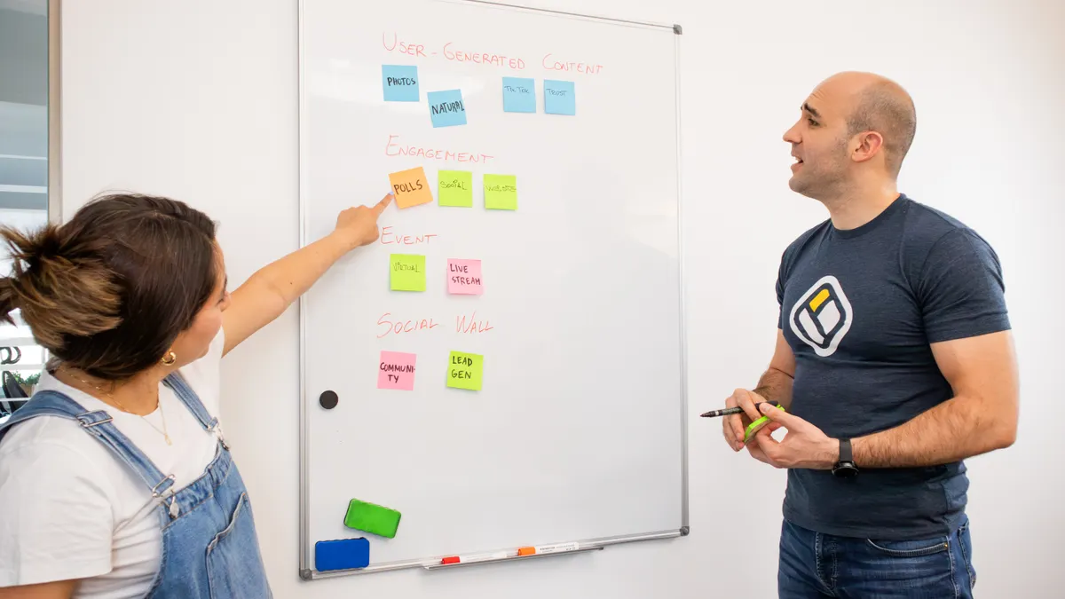 Two people planning ideas on a whiteboard with sticky notes