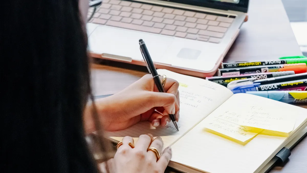 Best content writing software for SEO writers, marketers, and students — Woman Writing Notes in Front of Laptop