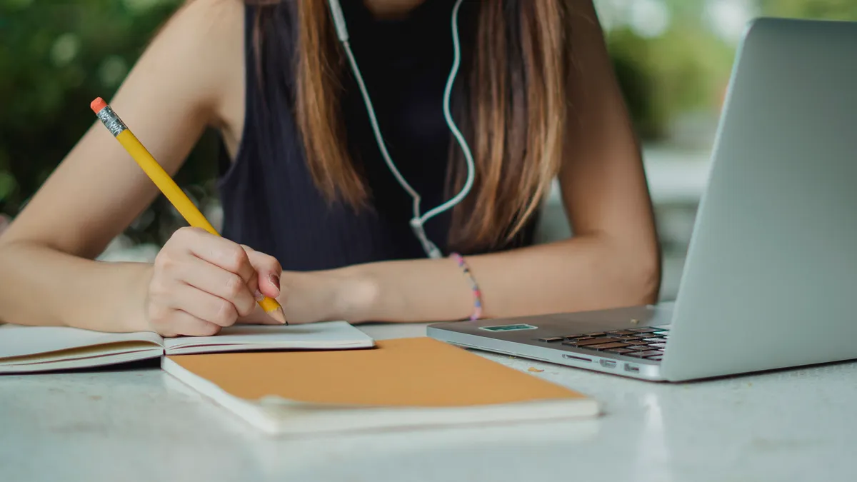 Best free content writing tools for students and solo creators — Crop female student writing notes in copybook while sit
