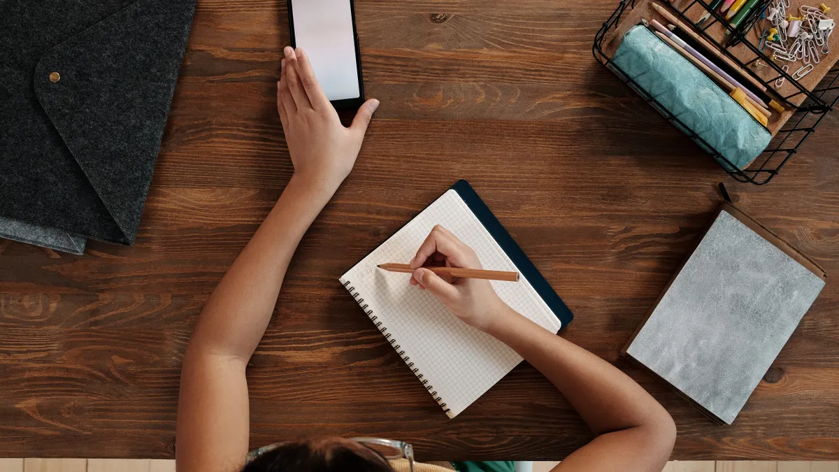 Best free content writing tools for students and solo creators — Girl Using Smartphone Writing in Notebook