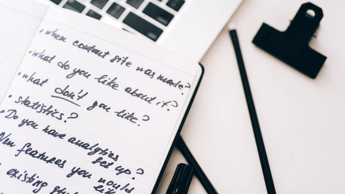 open notebook with handwritten content-planning questions beside a laptop