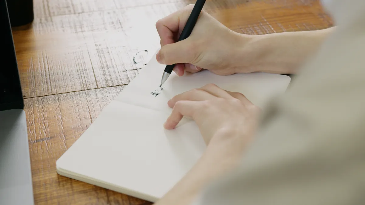 Hand sketching on a blank notebook page
