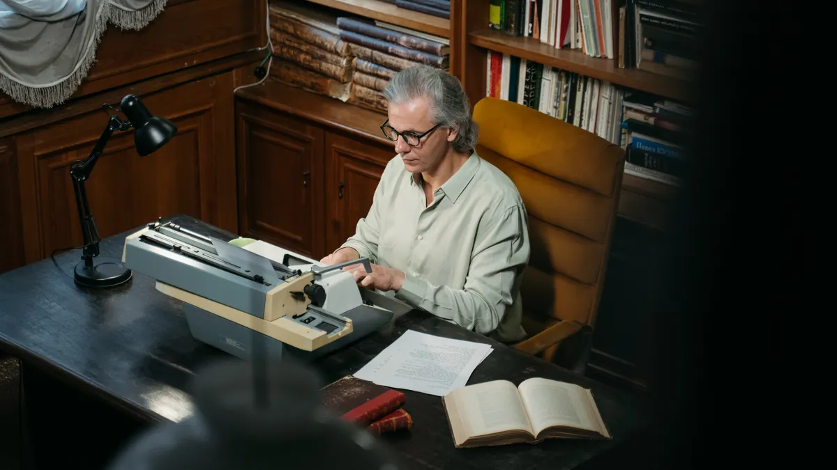 Person using a typewriter in a book-lined study